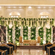 Luxurious wedding stage at Dehleez Banquet decorated with white flowers, greenery, chandeliers, and elegant seating.
