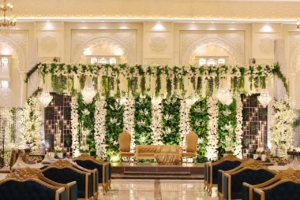 Luxurious wedding stage at Dehleez Banquet decorated with white flowers, greenery, chandeliers, and elegant seating.