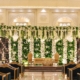 Luxurious wedding stage at Dehleez Banquet decorated with white flowers, greenery, chandeliers, and elegant seating.
