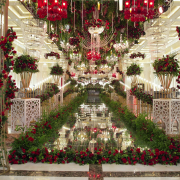 A lavishly decorated wedding stage adorned with red and white flowers, crystal chandeliers, and elegant golden structures, creating a grand and romantic ambiance.