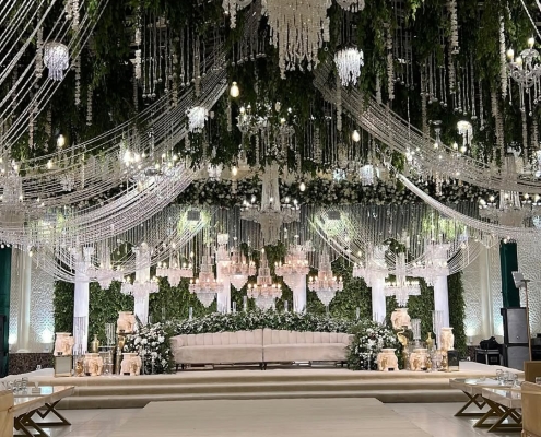 Elegant wedding stage with chandeliers and floral decor.
