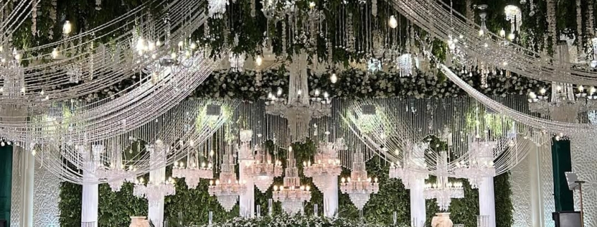 Elegant wedding stage with chandeliers and floral decor.